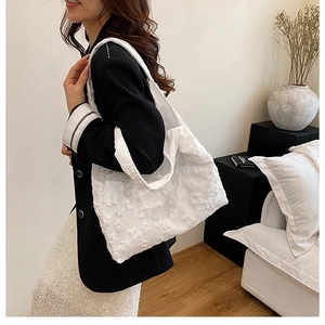 Detailed shot of white floral embroidery tote bag worn on shoulder by a model