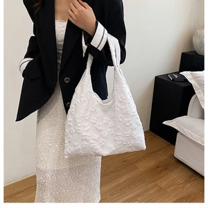 Detail of white tote bag featuring 3D floral texture styled with black blazer outfit