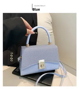 Detail view of light blue handbag featuring striped texture flap and golden twist-lock closure
