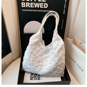 Detailed macro view of white floral lace tote bag with textured 3D embroidery pattern