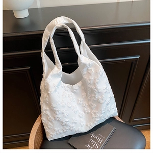 Close-up of white tote bag featuring 3D floral jacquard fabric and dual top handles