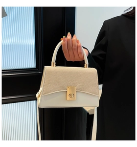 Detail of minimalist straw patchwork handbag with gold clasp and top handle