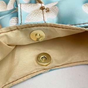Minimalist light blue floral shoulder bag with a secure golden magnetic buckle closure