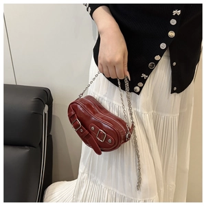 Close-up of deep red glossy underarm bag with silver buckle details and chain strap
