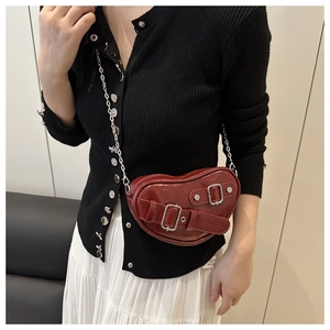 Détail du sac bandoulière rouge en cuir verni en forme de cœur avec boucles argentées