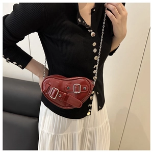 Détail du sac à bandoulière rouge en forme de cœur avec boucle argentée et rivets