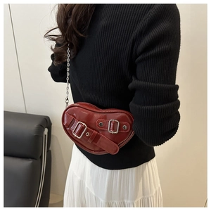 Détail du sac en cuir rouge en forme de cœur avec boucles et bandoulière chaîne