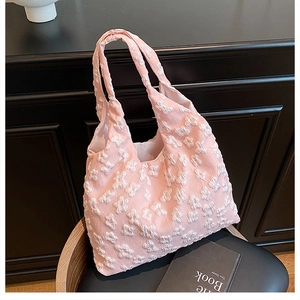Detail of light pink tote bag featuring 3D floral texture on a black leather chair