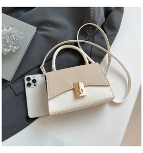 Detail view of contrast color crossbody bag with woven texture flap and gold lock hardware