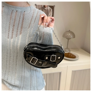 Close-up of black glossy leather underarm bag with silver buckles and chain strap detail