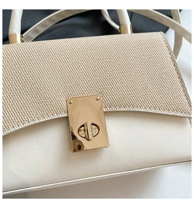 Detail of contrast stitch handbag with woven texture flap and golden twist lock