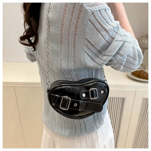 Détail d'un sac à bandoulière noir en forme de cœur avec chaîne argentée et boucle décorative