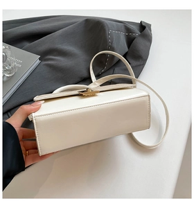 Detail shot of white rectangle handbag showing smooth leather texture and gold lock clasp