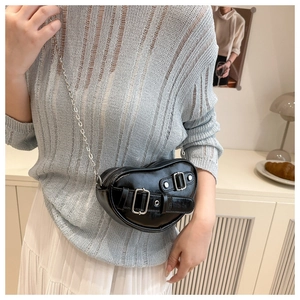 Close-up of black heart-shaped crossbody bag with silver buckles and chain strap