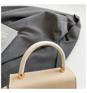 Detail of woven straw texture with cream leather handle and gold metal hardware