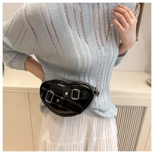 Détail d'un sac bandoulière noir en forme de cœur avec boucles et une fine bandoulière chaîne