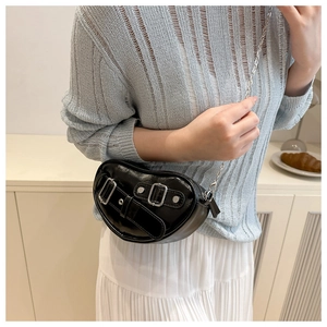 Détail d'un sac à bandoulière noir brillant en forme de cœur avec boucles métalliques