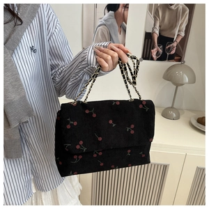 Détail du sac cabas en velours noir avec broderie cerise et bandoulière en chaîne