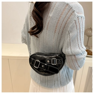 Detailed view of heart-shaped black leather crossbody bag with silver buckle and metal chain
