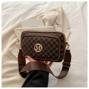 Detail of vintage monogram crossbody bag with golden M buckle and wide nylon strap