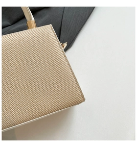 Detailed close-up of beige woven texture and white leather trim with gold hardware