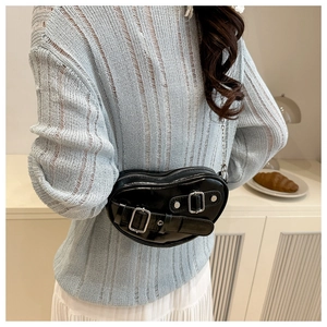 Détail d'un sac bandoulière noir en forme de cœur avec boucles et chaîne argentée