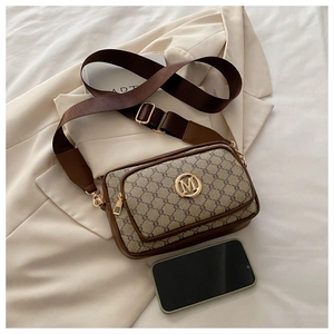 Detail of vintage monogram crossbody bag with golden M logo and wide nylon shoulder strap