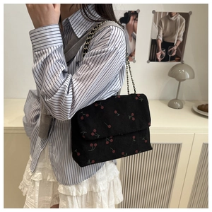 Détail du sac cabas en velours côtelé noir avec imprimé cerises et bandoulière chaîne