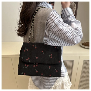 Détail du sac cabas en velours noir avec imprimé cerises et bandoulière chaîne métal