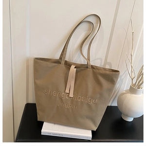 Close-up of khaki canvas tote bag with embroidery details and woven long handles