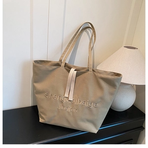 Detail of khaki canvas tote bag with elegant embroidery and long shoulder straps