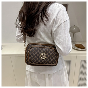 Detailed close-up of brown monogram crossbody bag with golden metal M logo buckle