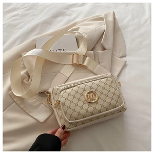 Detail of cream monogram crossbody bag with gold M logo and wide white nylon strap