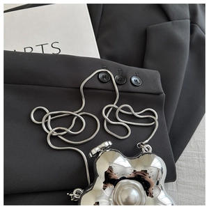 Detail of silver flower-shaped evening bag with large central pearl and snake chain