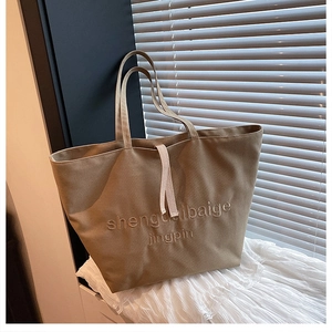 Detail of khaki canvas tote bag with textured embroidery and cream drawstring decor
