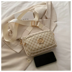 Detail of vintage patterned crossbody bag with golden M logo and wide fabric strap