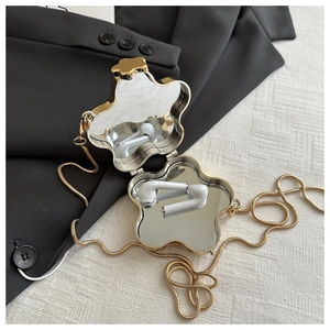 Detail view of flower-shaped gold metal mini bag with chain and internal vanity mirrors