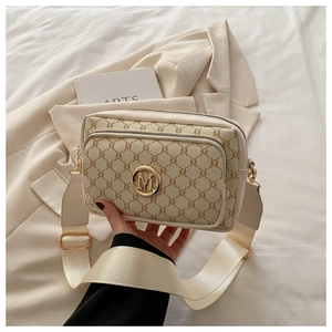 Detail of monogram pattern beige crossbody bag with gold M logo and wide fabric strap