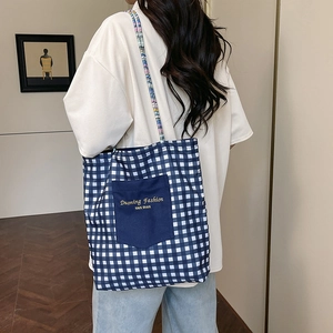 Reversible checkered denim tote bag with blue pocket and woven straps for commuting