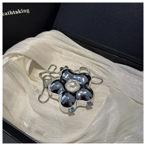 Close-up of silver floral evening bag with pearl center on white satin in a gift box