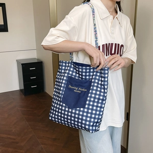 Blue and white checkered canvas tote bag with woven shoulder strap and front pocket