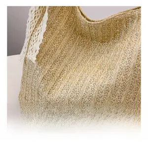Detail shot of the natural woven straw texture and white crochet lace trim on the tote bag