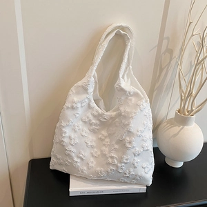 Elegant white floral embossed tote bag for women placed on books in a cozy setting