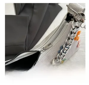 Detailed close-up of smooth silver zipper and colorful crochet flowers on white bag