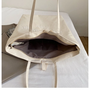 Detailed interior of the beige canvas tote bag showing the zipper pocket and lining