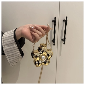Close-up of golden flower mini bag featuring a large central pearl and slim chain