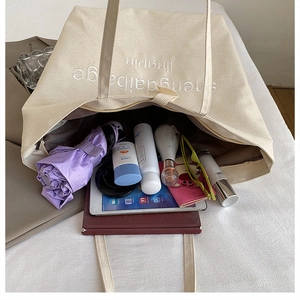 Detailed interior view of a beige canvas tote bag showing its large capacity for daily items