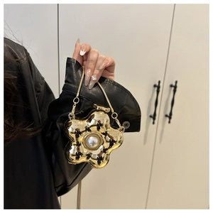 Detailed view of flower-shaped gold evening bag with high-gloss mirror finish and large pearl