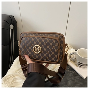 Close-up of vintage brown monogram bag with golden metal logo and wide fabric strap