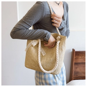 Close-up of woven straw handbag featuring a white lace bow and sturdy cotton rope handles